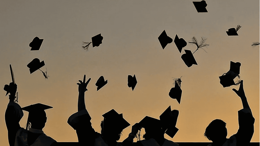 BITSOM graduates throwing graduation caps in the air at sunset