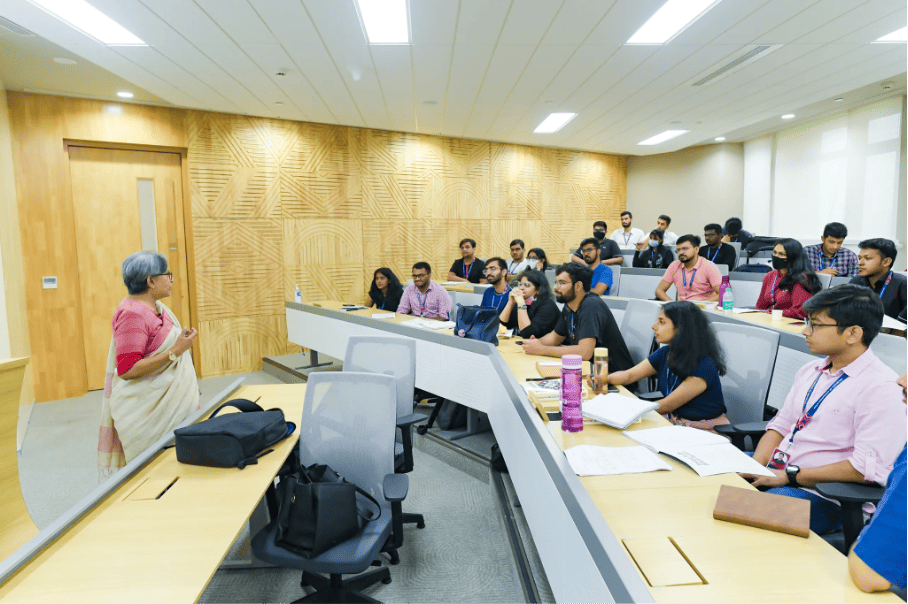 Dynamic classroom setting at BITSOM, with a professor engaging with a group of diverse students in an interactive session.
