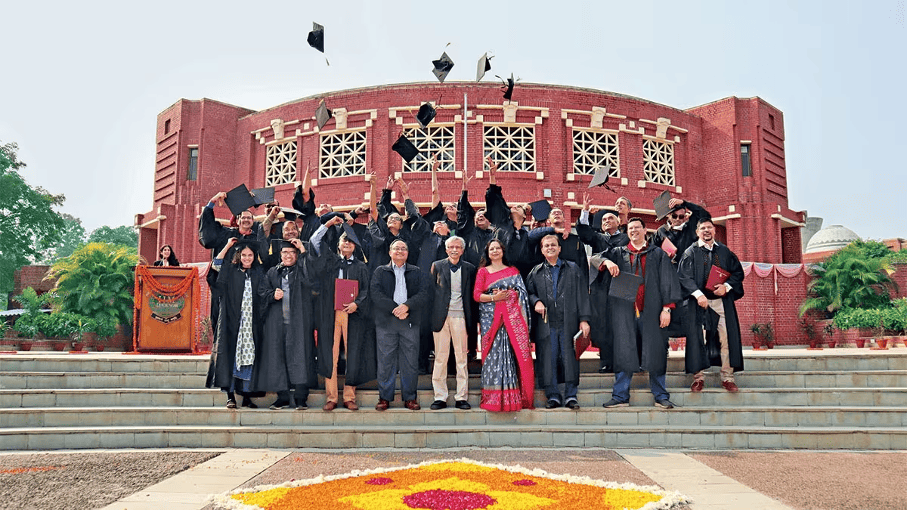 IIM Lucknow PGPEX graduates celebrating graduation outside the institute's main building.