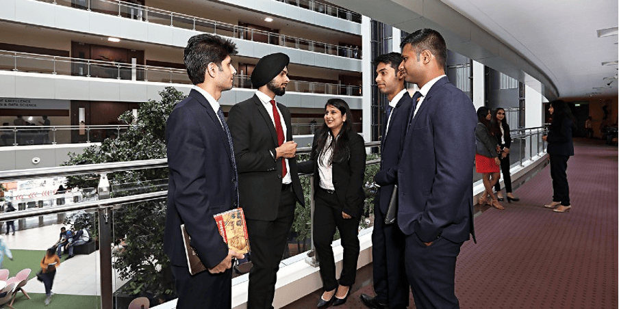 Business students in formal attire engaging in discussions at NMIMS