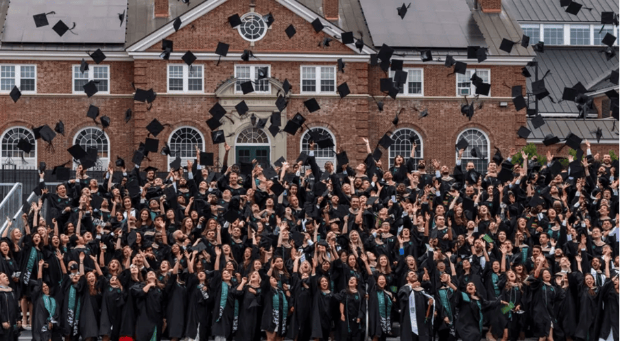 Joyous Tuck MBA graduates tossing caps in the air at commencement