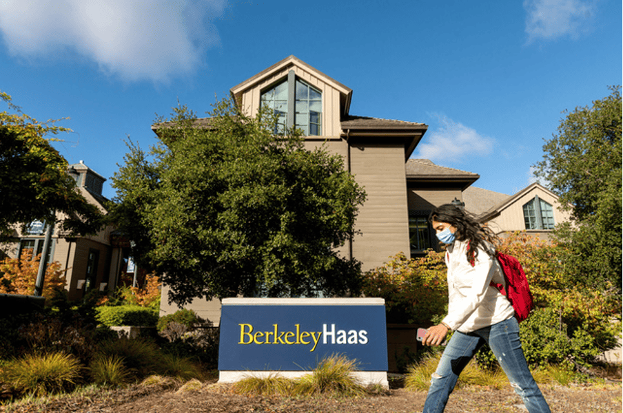 Student walking by the sign of UC Berkeley Haas School of Business
