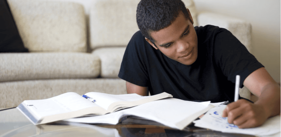 Young student studying at home with textbooks and notes